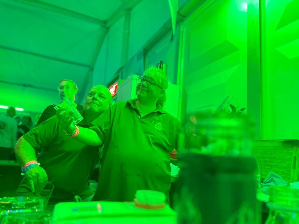 Schützenbruder umarmt eine Schützenschwester an der Theke der Sommernacht 2023 im grünen Licht