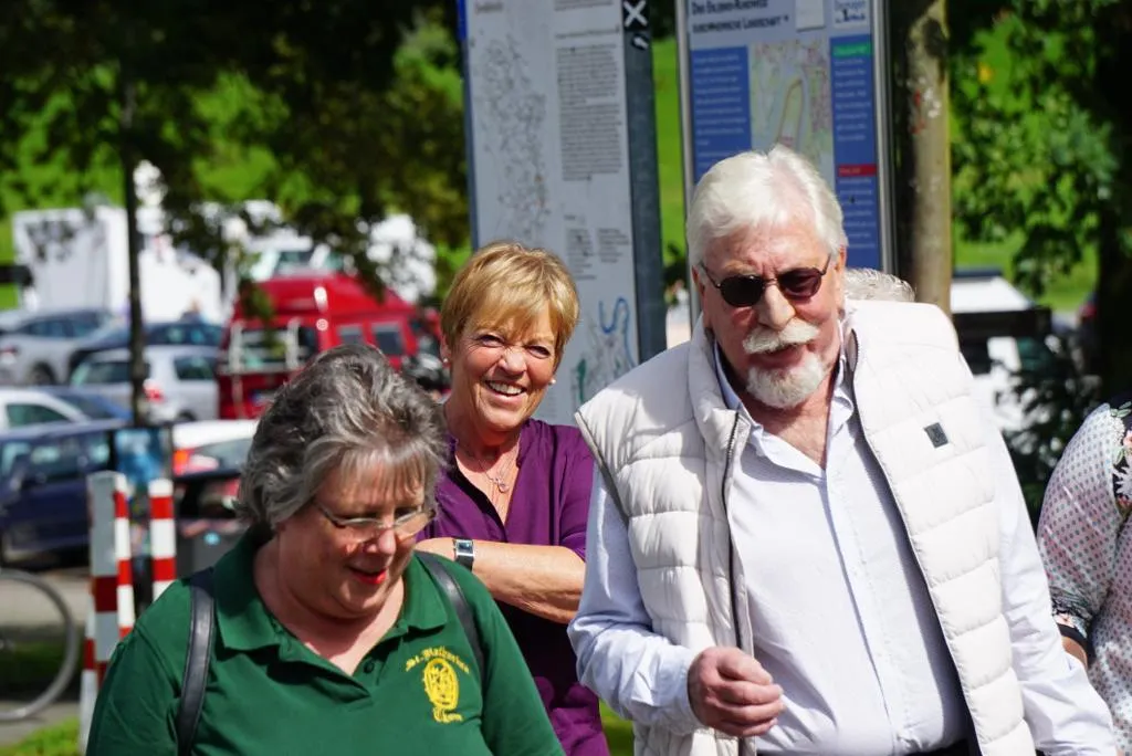Drei lachende Vereinsmitglieder an einer Infotafel beim Stadtrundgang durch Zons