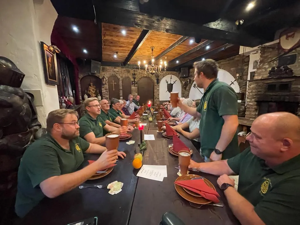 Lange Tafel im mittelalterlichen Gewölbe des Ritterschmaus, Bruderschaft prostet mit Tonkrügen zu