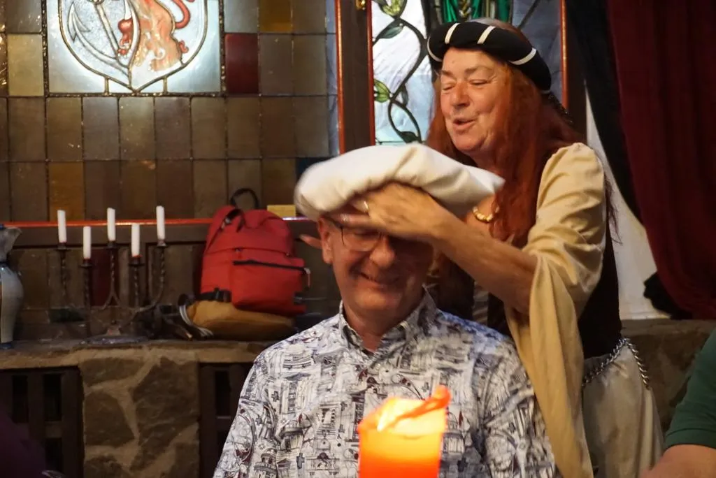 Mittelalterlich gekleidete Erzählerin setzt einem Schützenbruder eine weiße Haube auf
