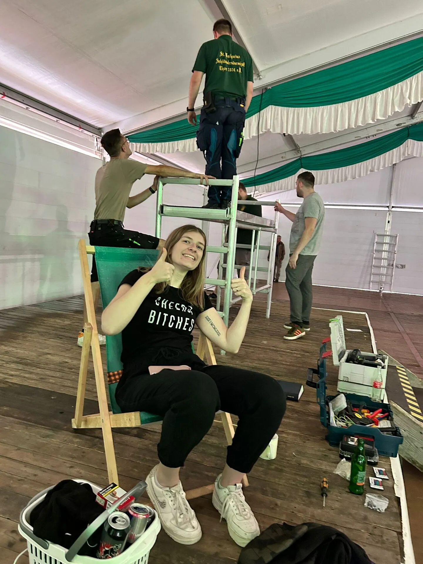Helfer bauen die Bühne im Festzelt auf, eine Helferin macht Pause im Liegestuhl
