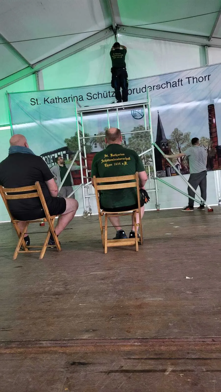 Anbringen des Vereinsbanners auf einem Rollgerüst hinter der Festzelt-Bühne