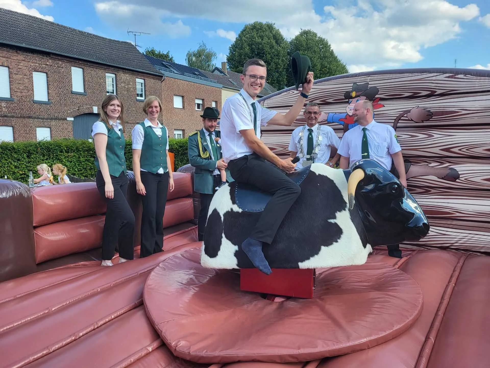 Bullriding-Szene mit Schützenbrüdern in Uniform um den Bullen herum