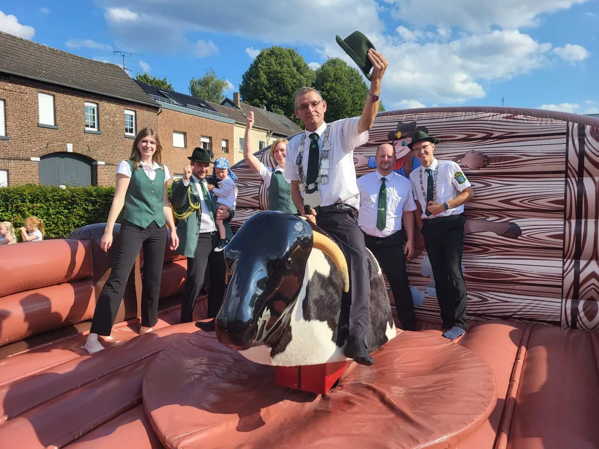 Bullriding beim Patronatsfest – Schützenkönig mit erhobenem Hut auf dem mechanischen Bullen